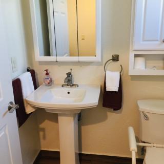 A clean and organized bathroom with a pedestal sink, mirror, and neatly hung towels.