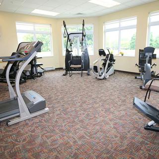 A well-lit gym with various cardio machines including treadmills and stationary bikes.