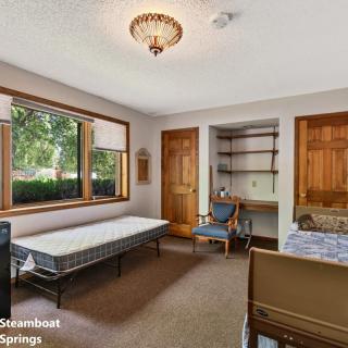 A cozy room with a large window, desk area, and simple furnishings.