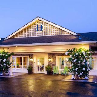 An inviting hotel exterior with warm lighting and landscaped surroundings during the evening.