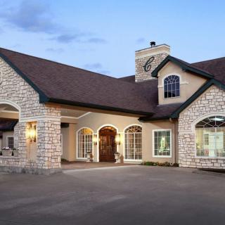A beautiful stone-exterior house with a well-lit entrance at dusk.