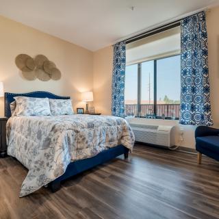 A stylishly decorated bedroom with a cozy bed, large window, and modern furnishings.
