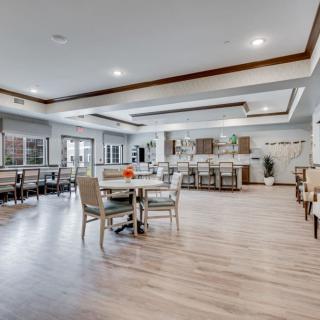 A spacious and modern dining area with wood flooring, tables, and chairs in an open layout.