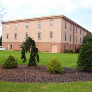 A modern multi-story building surrounded by well-maintained greenery.