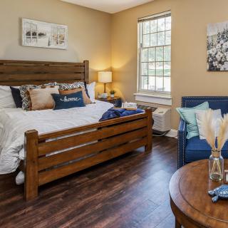 A cozy bedroom with a wooden bed frame, a comfortable blue couch, and warm lighting.