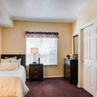 A cozy bedroom with a neatly made bed, nightstands, and a dresser under a window.