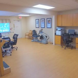 A spacious rehabilitation therapy room equipped with exercise machines and comfortable seating.