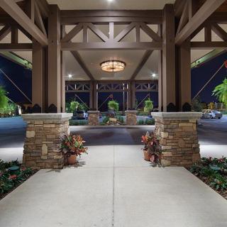 A well-lit entrance with stone pillars and decorative plants at night.