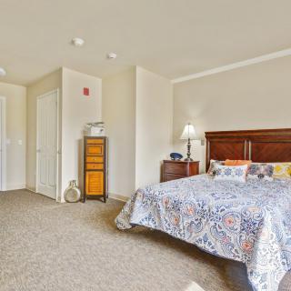 A cozy bedroom with a wooden headboard, patterned bedspread, and a bedside lamp.