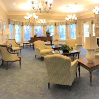 A spacious and elegant lounge area with plush seating, a grand piano, and large windows.