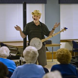 A performer playing the banjo in front of an audience.