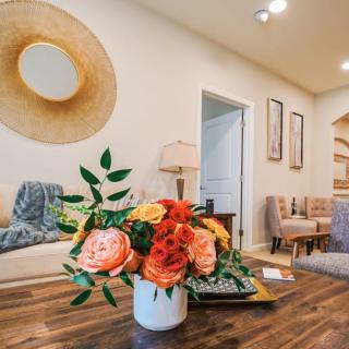 A cozy living room featuring a stylish floral arrangement on a wooden table, complemented by modern artwork and comfortable seating.