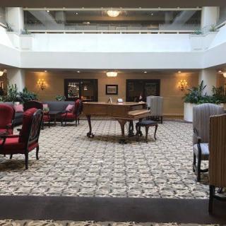 A spacious hotel lobby featuring a grand piano and comfortable seating areas.