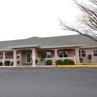 A commercial building with a parking lot in front, surrounded by trees.