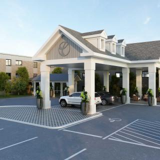 A hotel entrance with a covered driveway and parked cars.