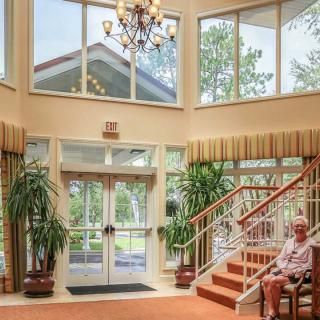 A spacious lobby with a grand chandelier, staircase, and large windows.