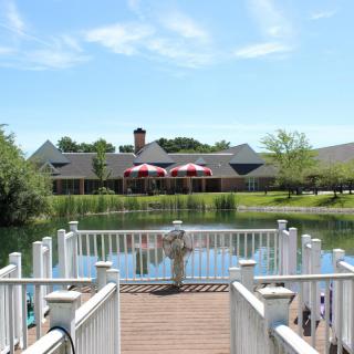 A scenic view from a dock overlooking a lake and a building in the distance on a clear day.