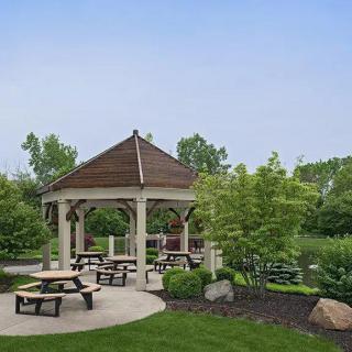 A scenic park featuring a gazebo surrounded by picnic tables and lush greenery.