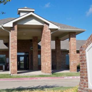 A brick building with large columns and a sloped roof under a clear blue sky.
