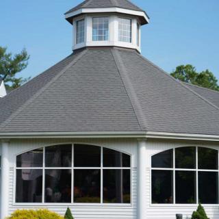 An octagonal gazebo with large windows and a pointed roof.