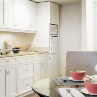 A modern kitchen with white cabinets and a cozy dining area.