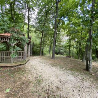A peaceful forest setting with a gazebo and pathway surrounded by trees.
