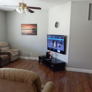 A cozy living room with recliners, a wall-mounted TV, and wooden flooring.
