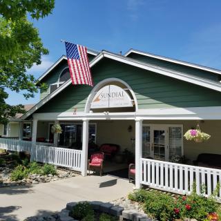 A charming house with a porch and an American flag, surrounded by a well-maintained garden under a clear blue sky.