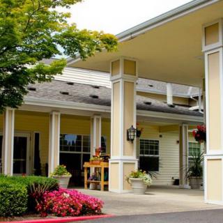 Entrance to a building with columns and landscaped surroundings.