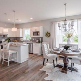 A modern open-concept kitchen and dining area with white cabinetry and abundant natural light.