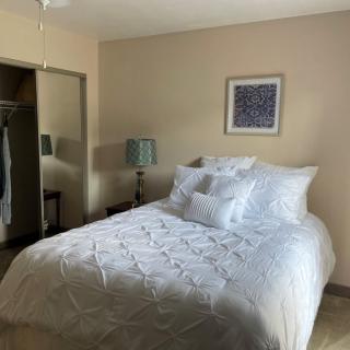 A cozy bedroom featuring a neatly made bed with white bedding, a bedside lamp, and artwork on the wall.