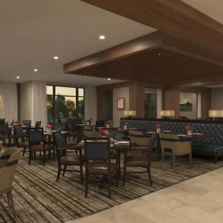 A modern restaurant dining area with neatly arranged tables and chairs, featuring warm lighting and elegant decor.