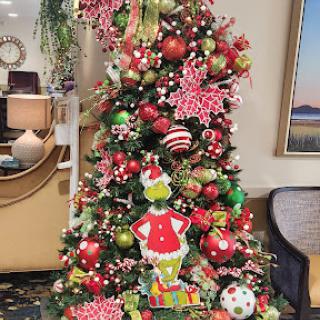 A beautifully decorated Christmas tree featuring vibrant ornaments and a playful Grinch figure.