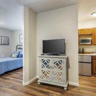 Compact apartment with a cozy bedroom and small kitchen area, featuring a TV stand in the living space.