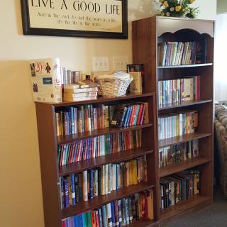 A cozy corner with two bookshelves filled with books and a decorative sign above.