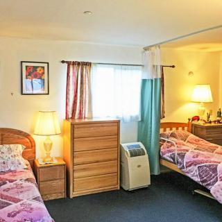 A cozy bedroom featuring twin beds, a dresser, and warm lighting.