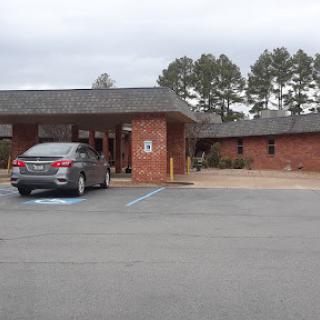 A view of a brick building with a parking area under cloudy skies.