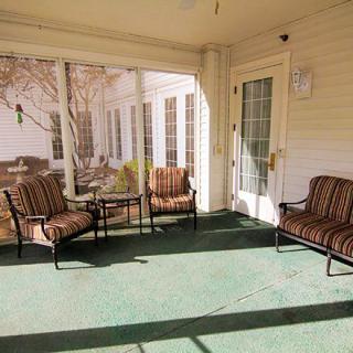 A cozy porch with cushioned chairs and a small table.