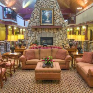 A cozy hotel lobby with comfortable seating, a stone fireplace, and warm lighting.