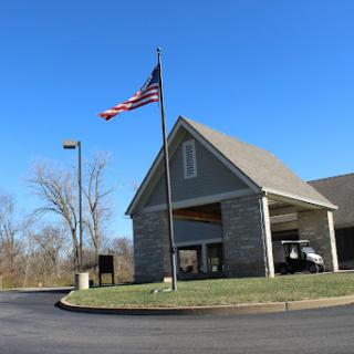 A stone-clad building featuring the American flag against a clear blue sky.