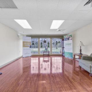 A bright and spacious empty office room featuring wooden flooring and large windows.