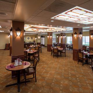 A spacious and elegantly decorated restaurant dining area with multiple tables and chairs.