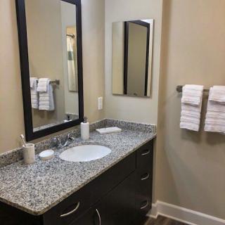 A modern bathroom with a granite countertop and neatly hung towels.