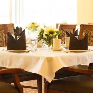 A beautifully set dining table with black napkins folded elegantly and a centerpiece of sunflowers.