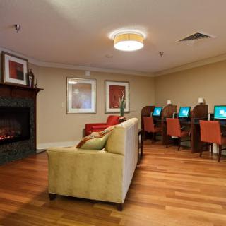 A cozy lounge area featuring a fireplace and computer workstations for guests.