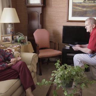 An engaging conversation between two elderly individuals in a cozy living room.