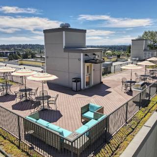 A bright and inviting rooftop lounge area with seating and umbrellas, perfect for relaxation in an urban setting.