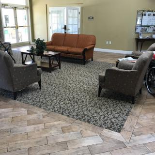A cozy lobby area featuring a sofa, armchairs, and decorative carpet.