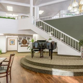 A spacious lobby with a grand piano and elegant staircase.