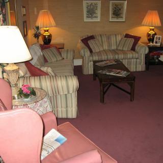 A cozy living room with sofas, armchairs, and warm lighting.